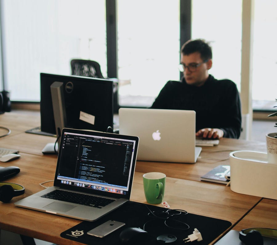 L'uomo In Camicia Nera Si Siede Dietro La Scrivania Con I Computer